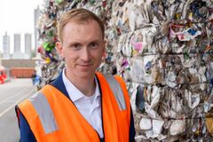 Forretningsleder Per Sigaard Christensen, teknologisk Institut, iført en orange sikkerhedsvest står foran stakke af komprimeret genbrugspapir.
