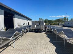 Mobilt vandrensningsanlæg omgivet af udfoldede solpaneler på en gårdsplads.