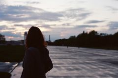 Kvinde ses bagfra på en tom gade, skyerne er grå og stemningen trist