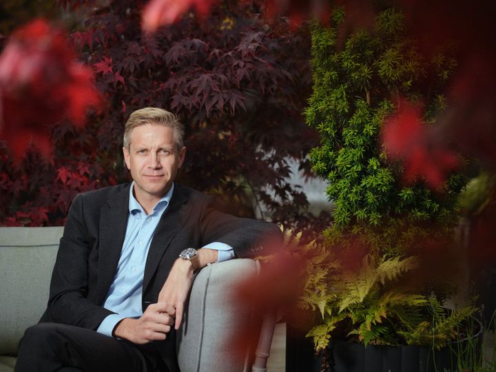 Portrætfoto af CEO Christian Jensby siddende i en efterårsramt have