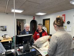 Lis Sørensen og Else Laursen står side og side og betjener kunder ved kassen. Foto: Blå Kors.