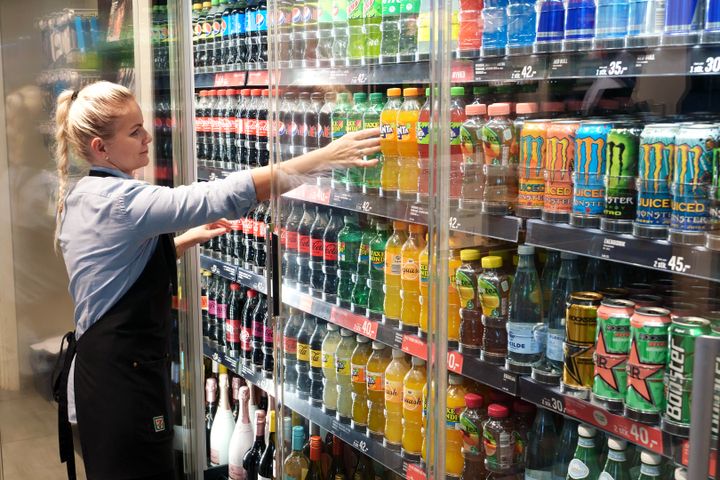 Kvindelig medarbejder sætter varer op på hylder i dagligvarebutik