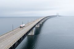 En lastbil kører over Øresundsbron, der strækker sig ud over havet mod horisonten under en gråvejrshimmel.