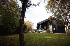 Sommerhus omgivet af træer og en grøn græsplæne, set udefra.