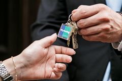 To mennesker rækker et sæt nøgler til hinanden, med en nøglebrik mærket "Nybolig".