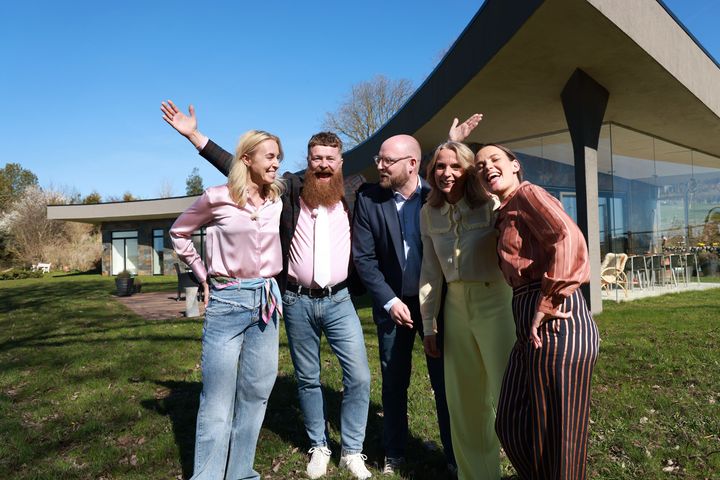 Gruppe mennesker står smilende udenfor en moderne bygning.