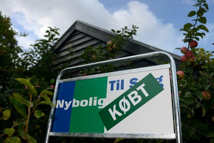 Et skilt foran et hus med teksten "Til Salg" og "KØBT" påskrevet.