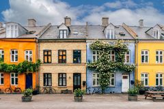 Række af farverige byhuse med klatreplanter og cykler foran.