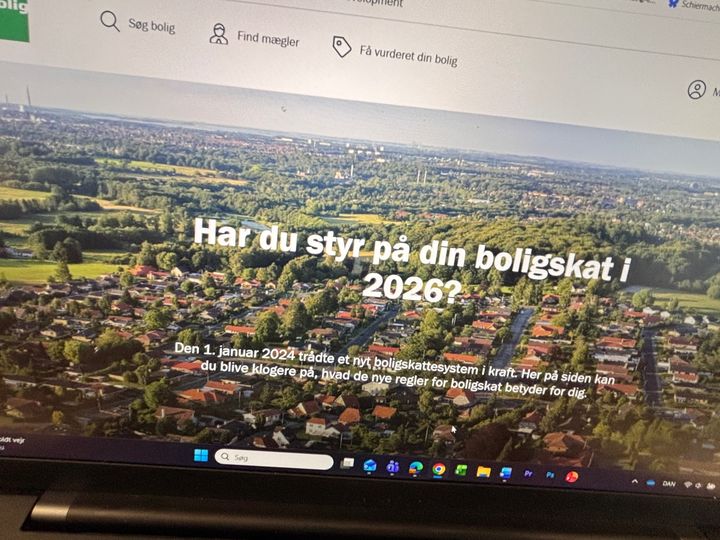 Laptopskærm viser en hjemmeside med overskriften: "Har du styr på din boligskat i 2026?" og information om nye regler fra 2024.