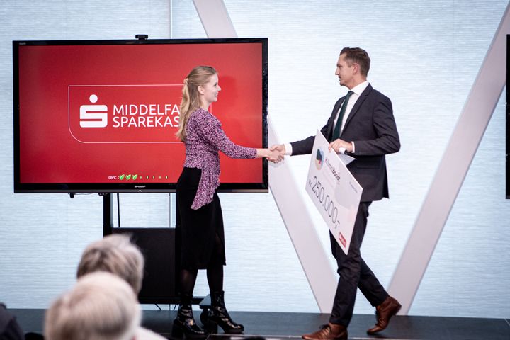 Sune Hasseltoft, erhvervschef i Middelfart Sparekasse, giver Line Kloster Pedersen det synlige bevis på, at hun er vinder af KlimaBoost 2023.